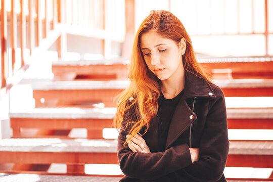 Depressed Young Woman In Black Clothes Looking Down And Sit On The Red Stairs Outdoors