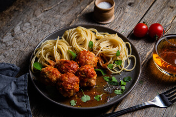 Pasta with meatballs and sauce in a plate on a wooden table