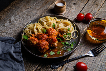 Pasta with meatballs and sauce in a plate on a wooden table