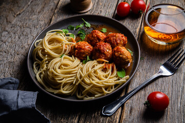 Pasta with meatballs and sauce in a plate on a wooden table