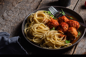 Pasta with meatballs and sauce in a plate on a wooden table