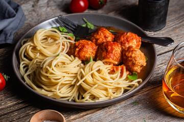 Pasta with meatballs and sauce in a plate on a wooden table