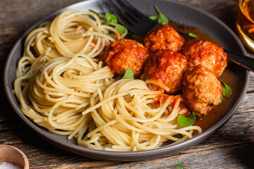 Pasta with meatballs and sauce in a plate on a wooden table