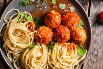 Pasta with meatballs and sauce in a plate on a wooden table