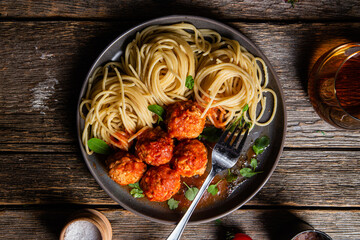 Pasta with meatballs and sauce in a plate on a wooden table