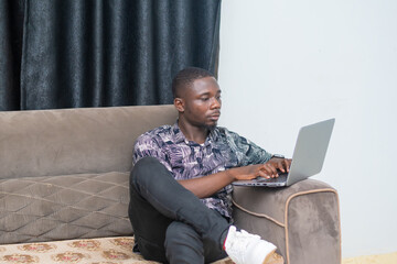 Good looking african businessman seated using his laptop, modern Technology