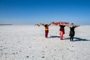 Colour in the endless white salt desert of the Rann of Kutch in Gujarat, women with scarves flying in the wind