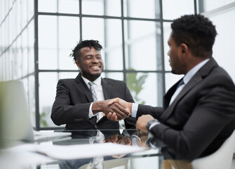 Shot of two young business men shaking hands in a modern office