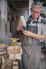 middle-aged man applying glue to a strip of wood to make a guitar