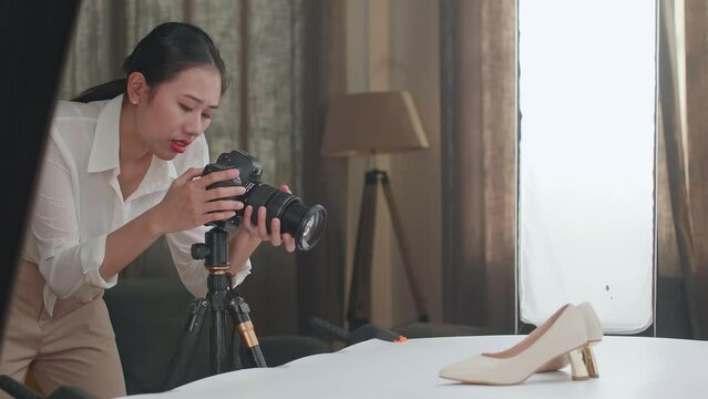 Asian Female Photographer Thinking Then Raising Her Index Finger While Taking Photos Of Them In Home Studio 
