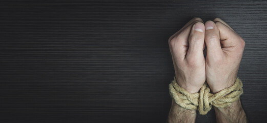 Male hands tied with a rope.