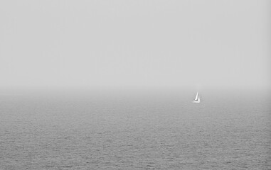 Sailing boat sailing on a calm sea with wind and fog.