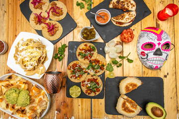 Obraz na płótnie Canvas Set of great Mexican food recipes with tacos al pastor, cochinita pibil tacos, nachos with guacamoles, quesadillas on wooden table