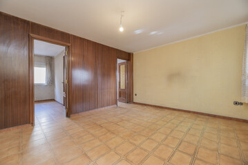 An empty room with poorly painted walls, doors made of sapele wood and a wall covered with the same...