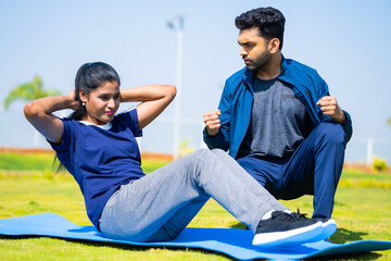 Fitness trainer encouraging or cheering up woman for exercising by pushing up limits - concept of motivation, guidance and athletic