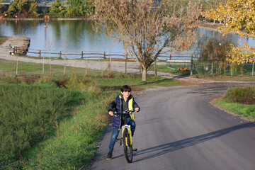 Obraz premium Happy teenager with bicycle on park road. Healthy lifestyle, environmentally transport concept.