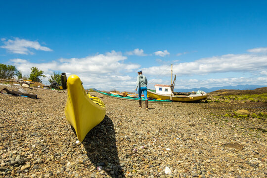 sea kayaks and a small artisanal subsistence fishing boat on a beach in the chonos archipelago patagonia chile. room for text