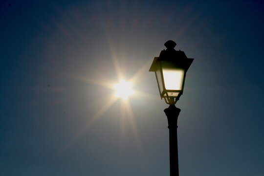street lamp on sky background, with sun.