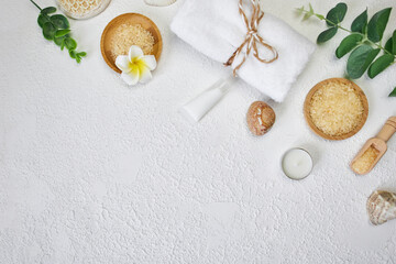 Spa treatment concept. Natural spa cosmetics products, sea salt, sea stone, massage brush, towel on white textured background from above. Spa background with a space for a text, flat lay, top view
