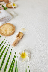 Obraz na płótnie Canvas Spa treatment concept. Natural spa products, sea salt, sea stone, massage brush, towel on white textured background from above. Spa background with a space for a text, flat lay, top view, vertical