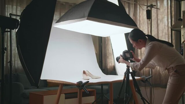 Asian Female Photographer Walking Into Home Studio And Taking Photos Of Women'S Shoes 
