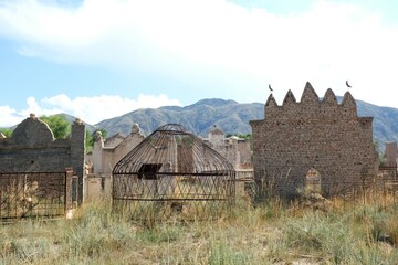 Tian Shan, Kyrgyzstan - circa August 2022: A traditional muslim cemetery at the foot of mountains...