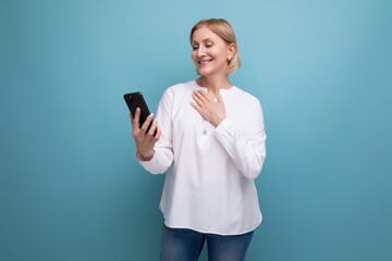 pensive slender blondie middle-aged woman in a white blouse masters the smartphone gadget