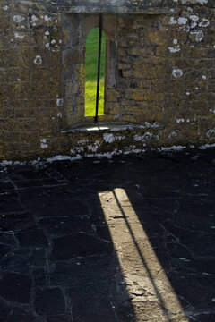 evening sun shining through a ruin window in an old abbey in Ireland