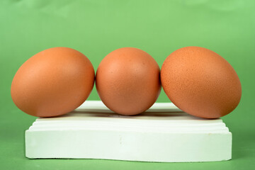 Fototapeta premium Chicken eggs on a white coaster on a green background.