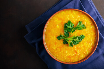 Red lentil soup on a dark brown background. Traditional lebanese or arabic lentil and vegetable spicy soup. Copy space
