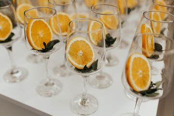 wine glasses on a white table with slice of oranges are preparing to create an aperol spritz.