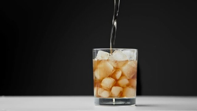 Drinking Coca Cola of Glass Cup with Ice and Wet Surface Close Up. Drink Sparkling Beverage or Diet Coke on Studio Shot in Macro. Eating of Colourful Pub Meal or Fast Food Isolated on Dark Background