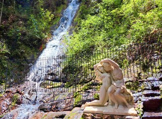 Po&ccedil;os de Caldas, Minas Gerais, Brazil - February 24, 2023. View of the waterfall and the statue of two young people embracing at Fonte do Amor. Famous tourist spot in the city of Po&ccedil;os de Caldas.