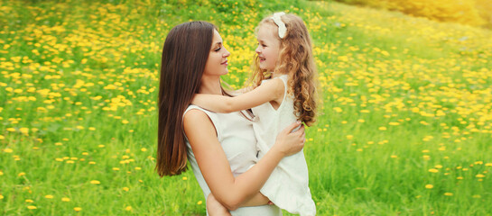 Portrait of happy smiling mother with little girl child on the grass in a summer park