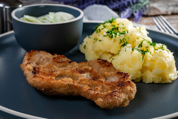 Pork chop served with mashed potatoes and cucumber salad.