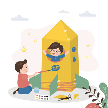 Little boys build rocket out of cardboard and paper. Cute child uses watercolor paints and paints toy spaceship. Imagination, preschoolers play astronauts