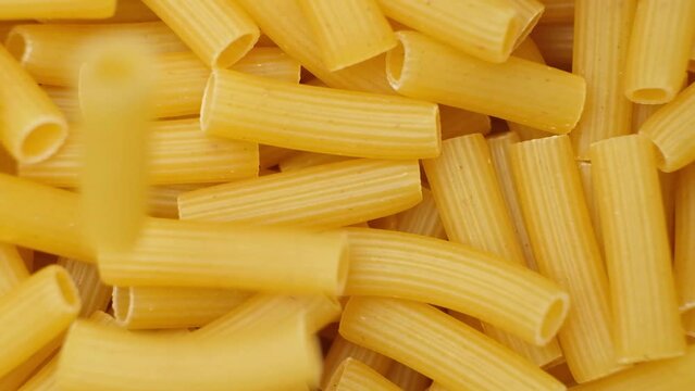 Flying wheat pasta Rigatoni in the form of tubes fall from top to bottom, close-up, slow motion shooting.