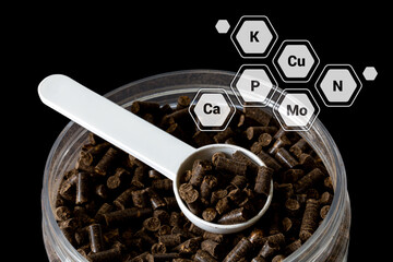 Organic granular fertilizer from biohumus, sapropel and seaweed in measuring spoon in a jar,...