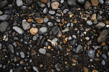 black and white pebbles and stones on the ground, background texture of sand and rocks