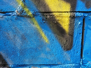 Fragment of an old wall painted with blue paint and spray paint, Lodz, Poland.