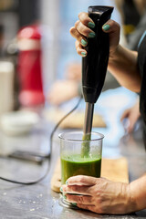 the cook prepares a vegetable puree with a hand blender, close-up. Preparation of broccoli cream...