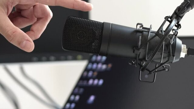 Finger tap microphone test. Finger touches mic, computer and recording stage background. Testing a microphone before a radio broadcast or streaming podcast social media network. Sound check speaker