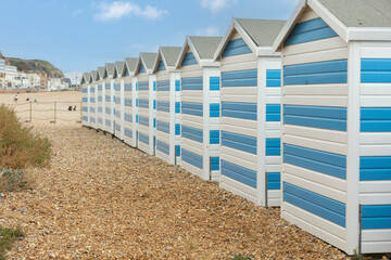 Hastings, united kingdom, 24, August 2022 Blue and white striped beach houses on a sunny beach in hastings - Powered by Adobe