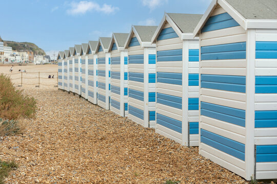 Hastings, united kingdom, 24, August 2022 Blue and white striped beach houses on a sunny beach in hastings