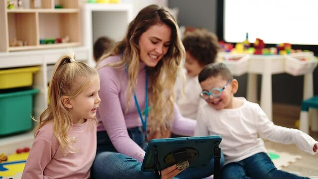 Woman and group of kids having lesson using touchpad at kindergarten