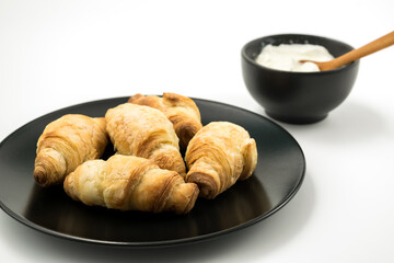 Traditional rolled dough called Kiflice served wuth yogurt on black plate and white background