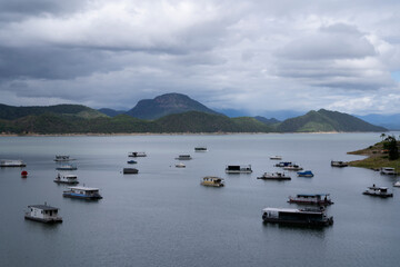 Fototapeta premium View of the houseboats, lake and hills under a cloudy sky. 