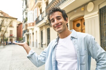 Young handsome caucasian man at outdoor showing a copy space on a palm and holding another hand on...