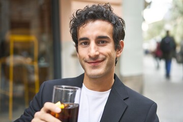 Young businessman enjoying a refreshing cola drink while networking at a sophisticated bar.