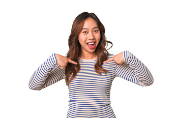 A young chinese woman surprised pointing with finger, smiling broadly.